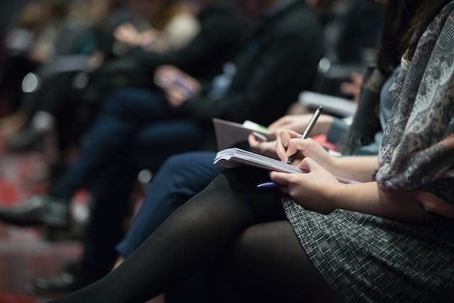 A person taking notes during a conference - Photo by The Climate Reality Project on Unsplash.